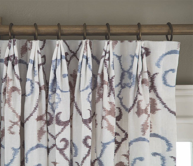 Euro pleated drapes on a wood curtain rod.