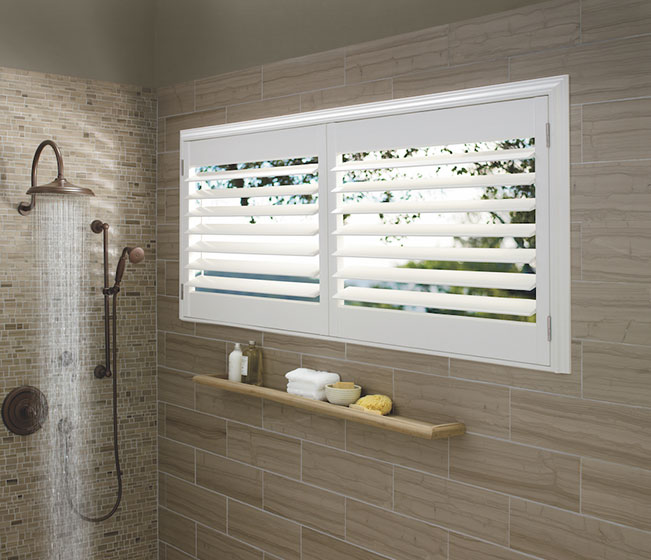 A modern shower with white shutters on the window.